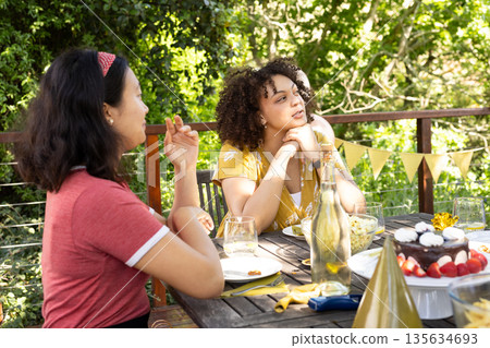 Friends enjoying outdoor celebration with food and drinks on sunny day Friends enjoying outdoor celebration with food and drinks on sunny day 135634693