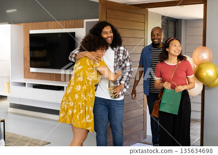 Friends celebrating at home, hugging and smiling with balloons and gifts 135634698