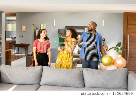 At home, friends celebrating with gifts and balloons, smiling together happily 135634699
