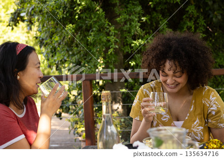 At outdoor gathering, friends laughing and drinking together, having fun At outdoor gathering, friends laughing and drinking together, having fun 135634716
