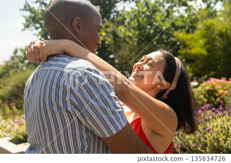 Couple embracing outdoors, smiling and enjoying sunny day in garden Couple embracing outdoors, smiling and enjoying sunny day in garden 135634726