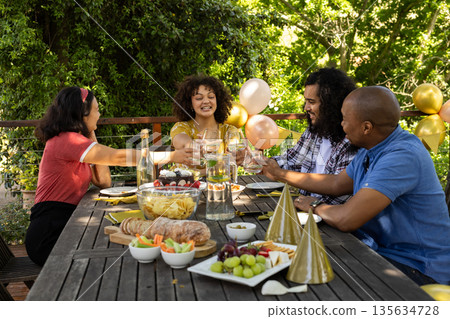 Toasting with wine glasses, friends celebrating and sharing festive meal outdoors Toasting with wine glasses, friends celebrating and sharing festive meal outdoors 135634728