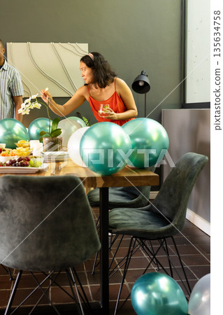 Woman decorating table with balloons and flowers, preparing for celebration at home 135634758