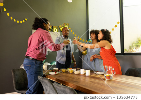 Celebrating at home, friends toasting drinks with joyful smiles and laughter Celebrating at home, friends toasting drinks with joyful smiles and laughter 135634773