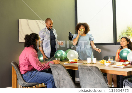 Friends celebrating with drinks and snacks around table, enjoying festive gathering Friends celebrating with drinks and snacks around table, enjoying festive gathering 135634775