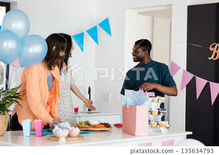 Celebrating birthday at home, friends with balloons, cupcakes, and gifts, smiling 135634793