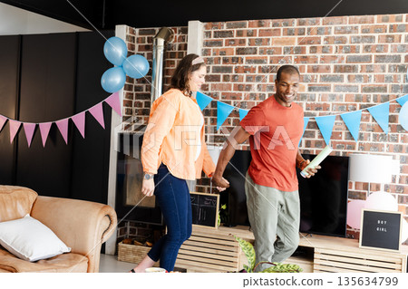 Couple celebrating gender reveal party at home with joyful expressions Couple celebrating gender reveal party at home with joyful expressions 135634799