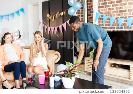 Man serving drinks at baby shower, guests smiling and enjoying celebration Man serving drinks at baby shower, guests smiling and enjoying celebration 135634802