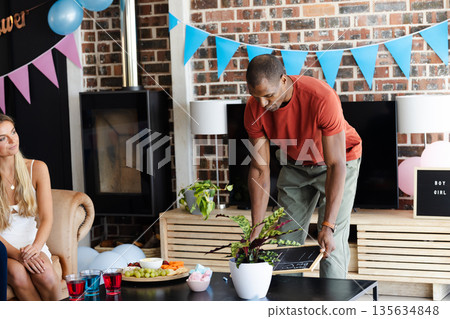 African American man preparing party decorations at home with snacks and drinks 135634848