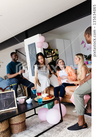 Friends enjoying casual gathering at home, chatting and sharing snacks together Friends enjoying casual gathering at home, chatting and sharing snacks together 135634865