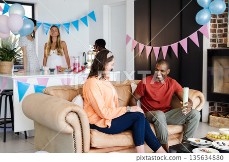 Friends enjoying casual gathering at home with festive decorations and snacks Friends enjoying casual gathering at home with festive decorations and snacks 135634880