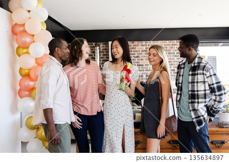 Group of friends celebrating with gift and balloons, smiling and enjoying together Group of friends celebrating with gift and balloons, smiling and enjoying together 135634897