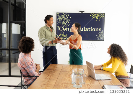 Celebrating achievement, colleagues presenting award with smiles and applause in office 135635251