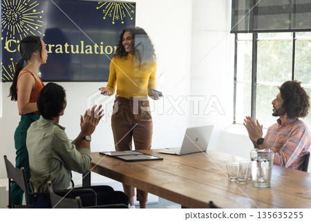 Team celebrating success in office meeting room, woman smiling and holding award Team celebrating success in office meeting room, woman smiling and holding award 135635255