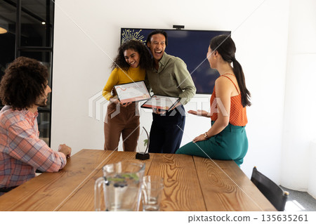 Colleagues celebrating achievement with certificates in modern office meeting room 135635261
