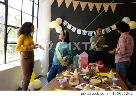 Colleagues enjoying baby shower celebration at office with snacks and decorations 135635262