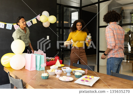 Celebrating office party, colleagues sharing snacks and gifts in festive atmosphere 135635270