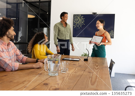 Receiving award, businesswoman smiling as colleagues applaud during office meeting Receiving award, businesswoman smiling as colleagues applaud during office meeting 135635273