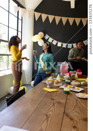 Celebrating at office party, colleagues chatting and having snacks and drinks Celebrating at office party, colleagues chatting and having snacks and drinks 135635276