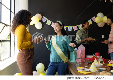 Celebrating baby shower, diverse friends enjoying conversation and snacks at party Celebrating baby shower, diverse friends enjoying conversation and snacks at party 135635289