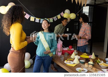 Celebrating baby shower, diverse friends enjoying food and conversation at home Celebrating baby shower, diverse friends enjoying food and conversation at home 135635305