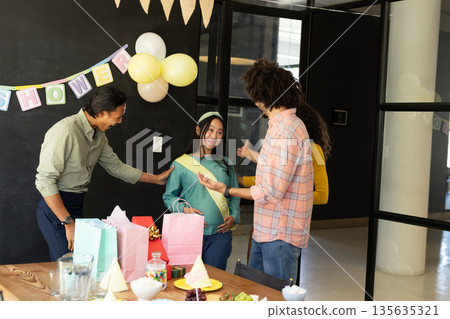 In office, diverse group celebrating baby shower, congratulating expectant mother 135635321