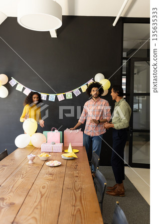 Colleagues preparing for office celebration with balloons and gift bags Colleagues preparing for office celebration with balloons and gift bags 135635333