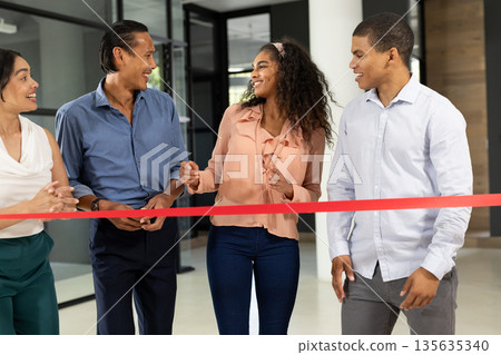 Diverse business team celebrating ribbon-cutting ceremony in modern office space 135635340