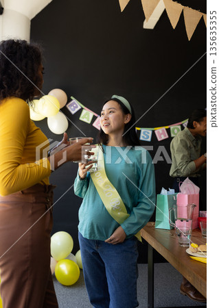 Pregnant woman at baby shower talking with friend, enjoying celebration 135635355