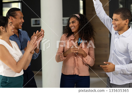 Diverse business team celebrating success together in modern office environment 135635365