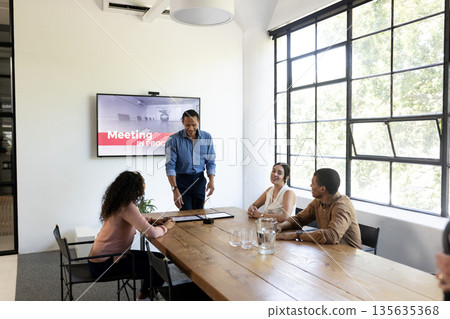 Discussing project, business team collaborating around conference table in modern office 135635368