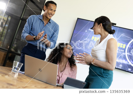 Diverse business team discussing project with laptop and tablet in modern office 135635369