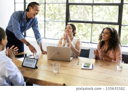 Business team celebrating success in office meeting with laptops and tablets 135635382