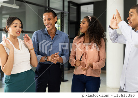 Diverse business team discussing ideas and laughing together in modern office 135635386