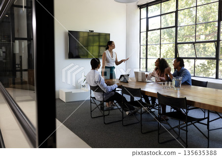 Business team discussing strategy in modern office with large windows 135635388