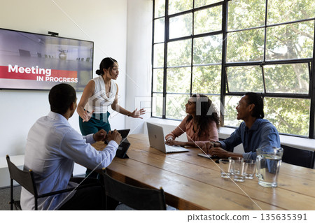Business meeting in office, diverse team discussing ideas around conference table 135635391