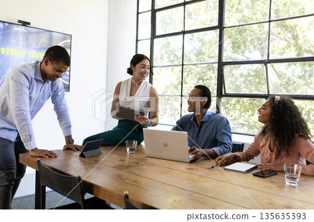 Diverse business team collaborating with laptops and tablets in modern office Diverse business team collaborating with laptops and tablets in modern office 135635393