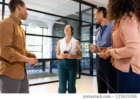 Diverse business team engaging in lively discussion at modern office 135635399