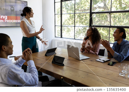 Business team in meeting room discussing project, smiling and engaging with ideas 135635400