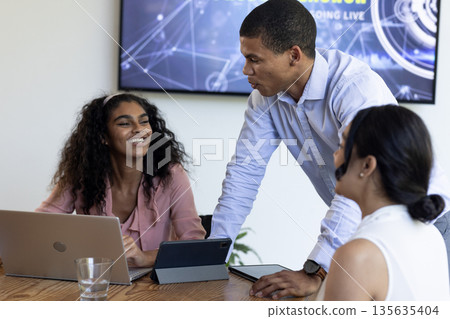 Discussing project with laptops, African American woman and colleagues in modern office 135635404