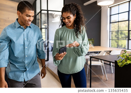 Walking through modern office, colleagues discussing project, smiling and engaged 135635435