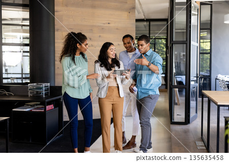Diverse business team discussing project while walking through modern office hallway 135635458
