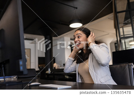 Businesswoman in office smiling while using headset for video conference call Businesswoman in office smiling while using headset for video conference call 135635478
