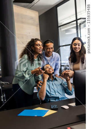 Diverse business team celebrating success together in modern office environment Diverse business team celebrating success together in modern office environment 135635486