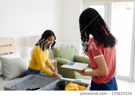 Mother and daughter packing suitcase at home, preparing for family vacation Mother and daughter packing suitcase at home, preparing for family vacation 135635528