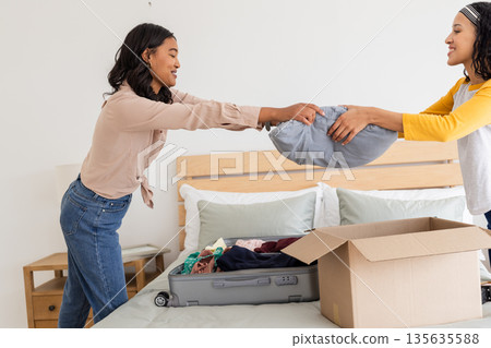 Mother and daughter packing suitcase together, preparing for family trip at home Mother and daughter packing suitcase together, preparing for family trip at home 135635588