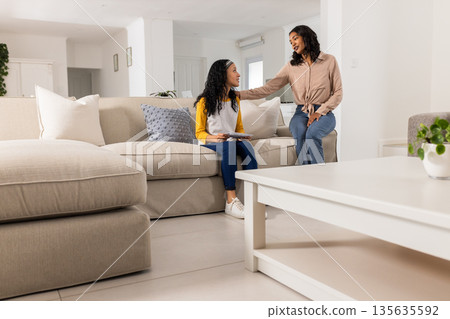 Mother and daughter talking on sofa at home, sharing quality time together Mother and daughter talking on sofa at home, sharing quality time together 135635592