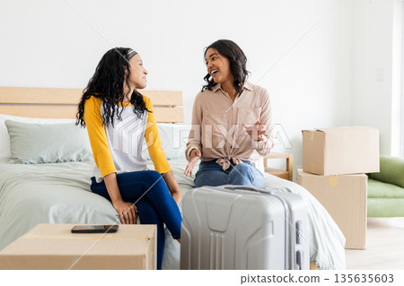 Mother and daughter discussing travel plans while packing suitcase in bedroom Mother and daughter discussing travel plans while packing suitcase in bedroom 135635603