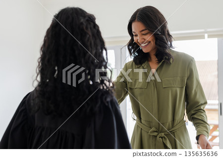 Smiling woman in green dress interacting with child at home, enjoying quality time 135635636