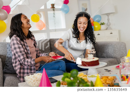 Celebrating birthday, two women laughing and cutting cake at home party Celebrating birthday, two women laughing and cutting cake at home party 135635649